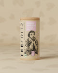 Runde Teedose mit Illustrationen, der Aufschrift "Frisch Verliebt" und "Hibiskus Minze"; Bio-Produktkennzeichnung.