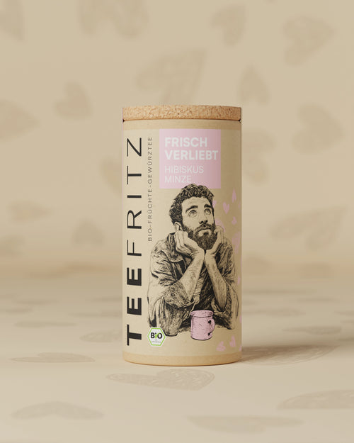 Runde Teedose mit Illustrationen, der Aufschrift "Frisch Verliebt" und "Hibiskus Minze"; Bio-Produktkennzeichnung.