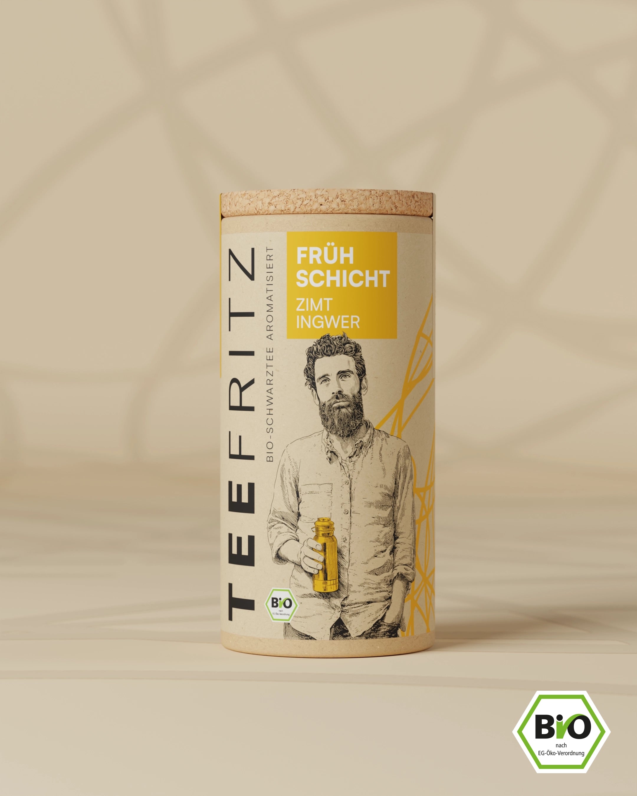 Runde Pappverpackung für aromatisierten Bio-Schwarztee mit einem illustrierten Mann, Zimt und Ingwer Geschmacksangabe.