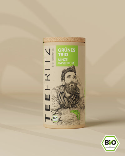 Runde Pappverpackung mit Bio-Grüntee, "Grünes Trio Minze Basilikum", und Zeichnung eines liegenden Mannes.